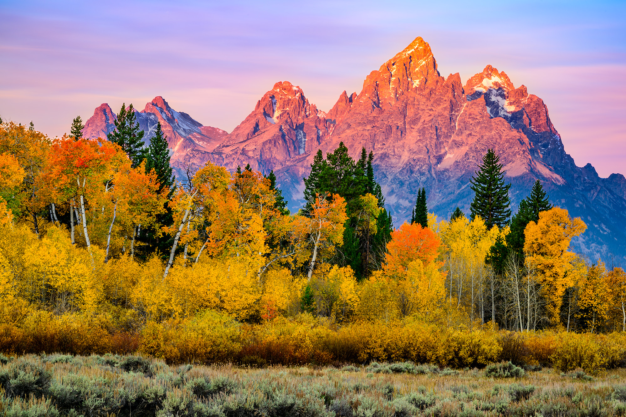 Soft morning rays light up the Grand Teton with brilliant fall colors setting the perfect foreground. Smoke from a wildfire in...