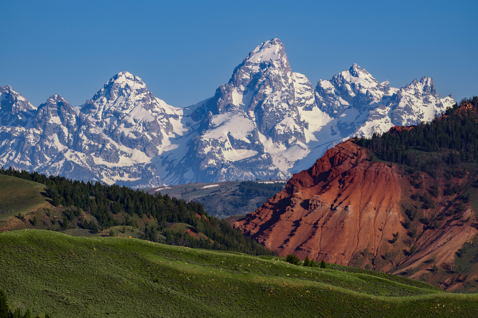 A peculiar and rarely seen view of the Teton mountains rising high above the surrounding ranges. This view from the Gros Ventre...