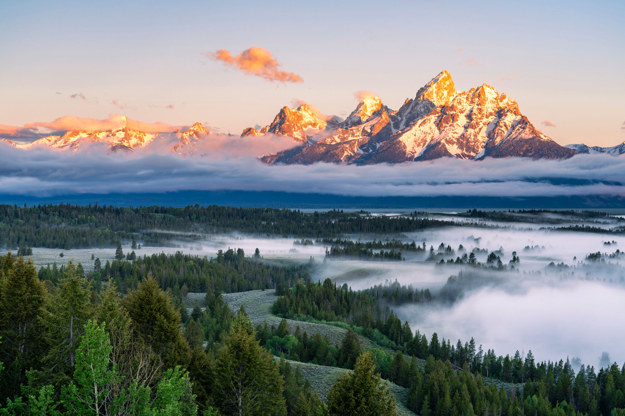 Early morning light brightens the Tetons after an overnight rainstorm while fog envelopes the lower elevations